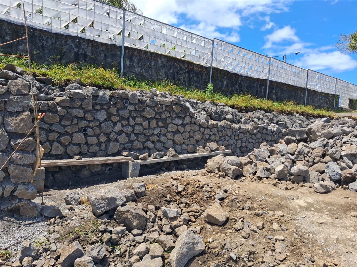 Mur de soutènement en moellons de pierre volcanique avec tuyaux de drainage, chantier PGLA à La Réunion